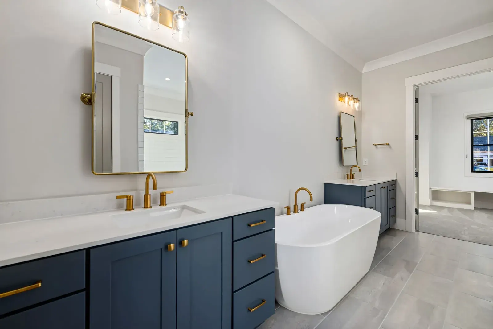 Navy double vanity with freestanding soaking tub and brass fixtures