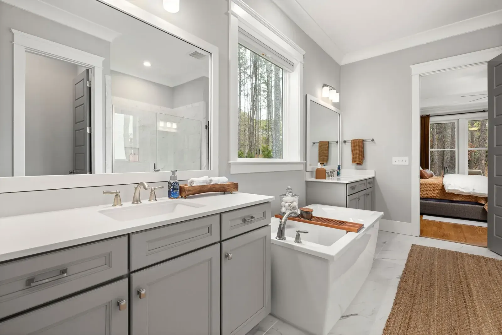 Bright primary bath with gray double vanity and soaking tub