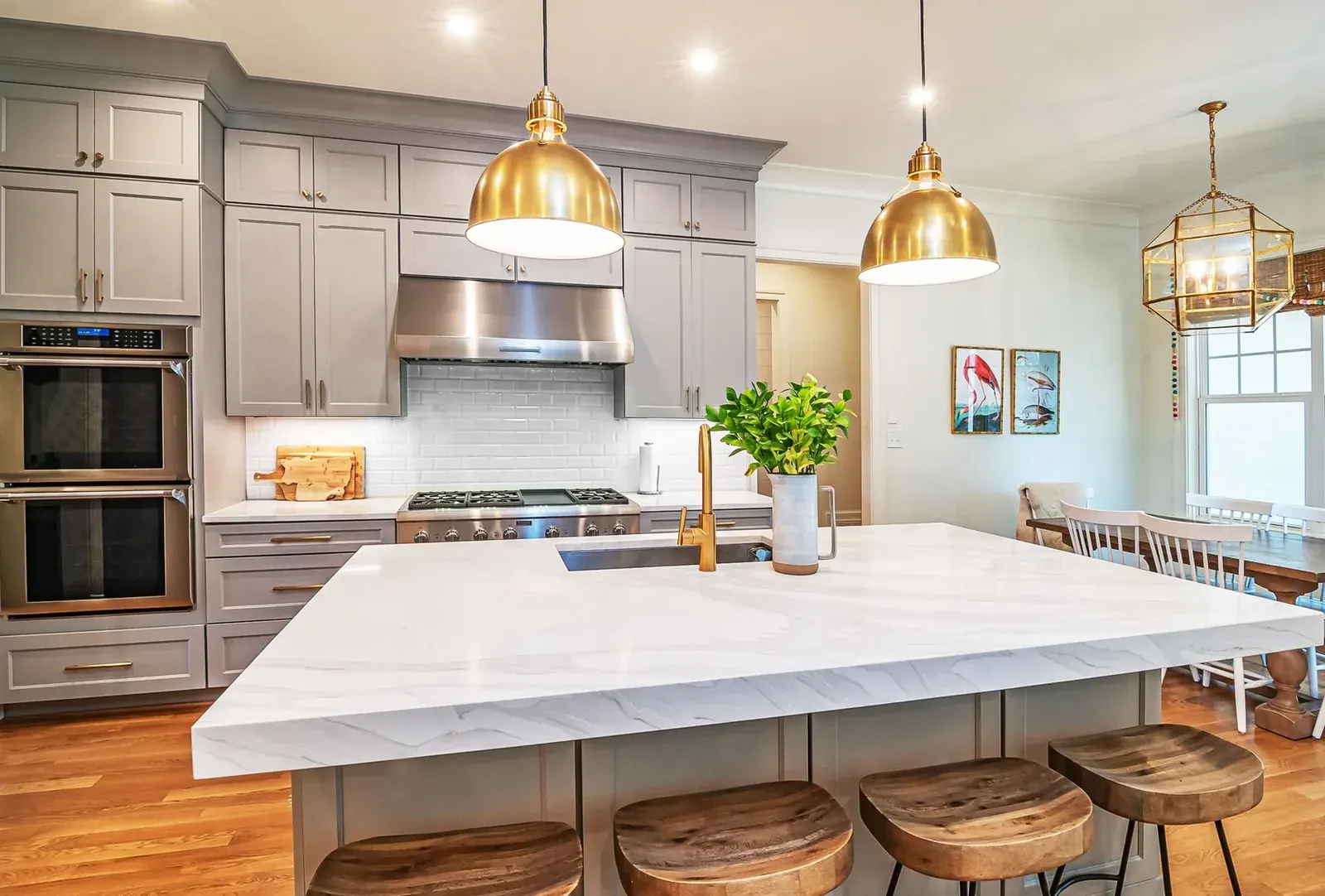 Open kitchen with marble-look island, gray cabinetry and brass pendant lights