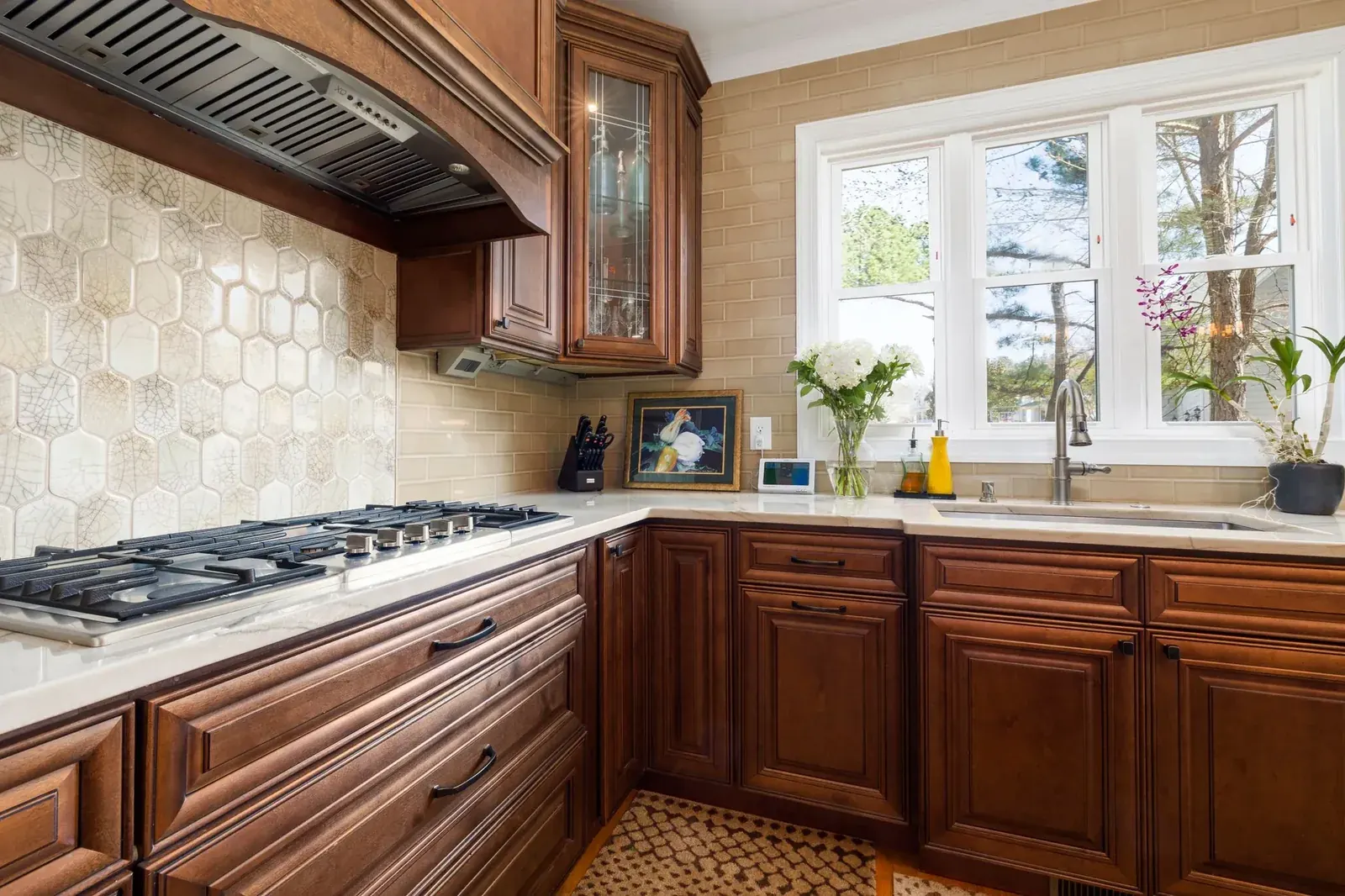 Warm wood cabinetry with stone-look tile backsplash and gas cooktop